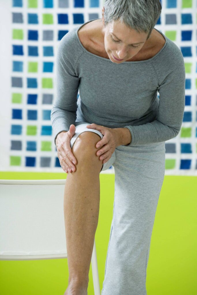 Senior woman examining her knee.