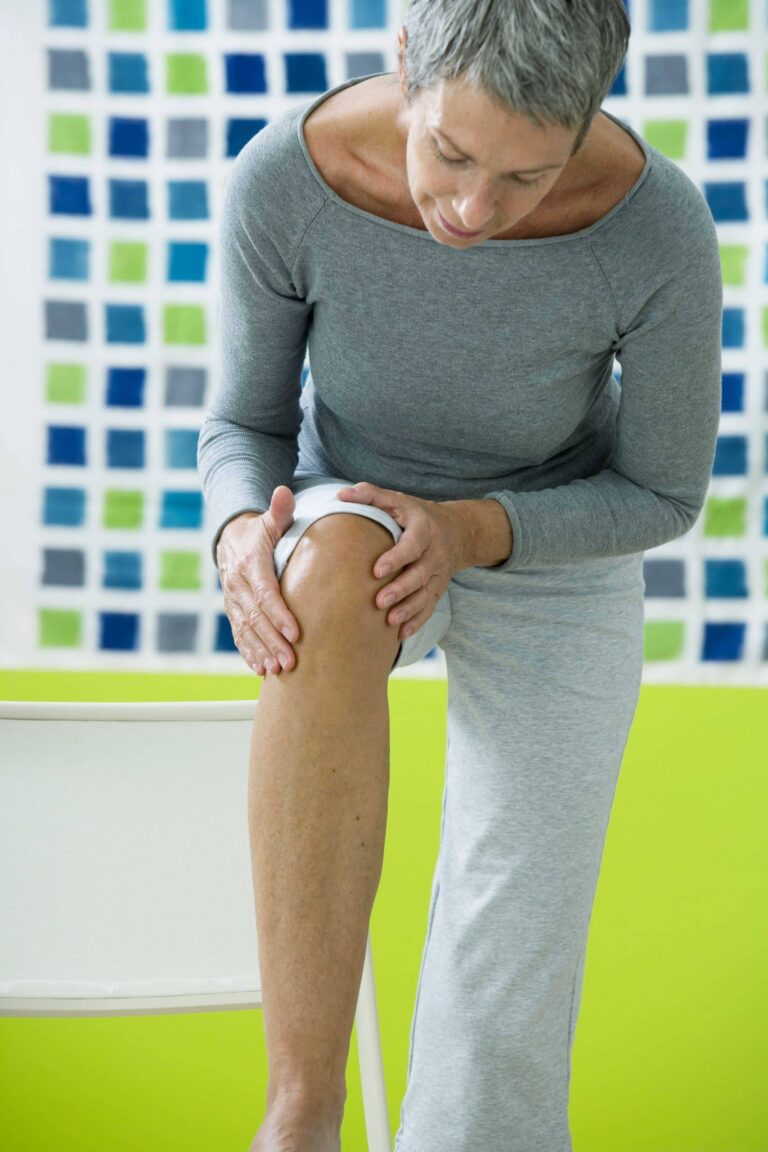 Senior woman examining her knee.