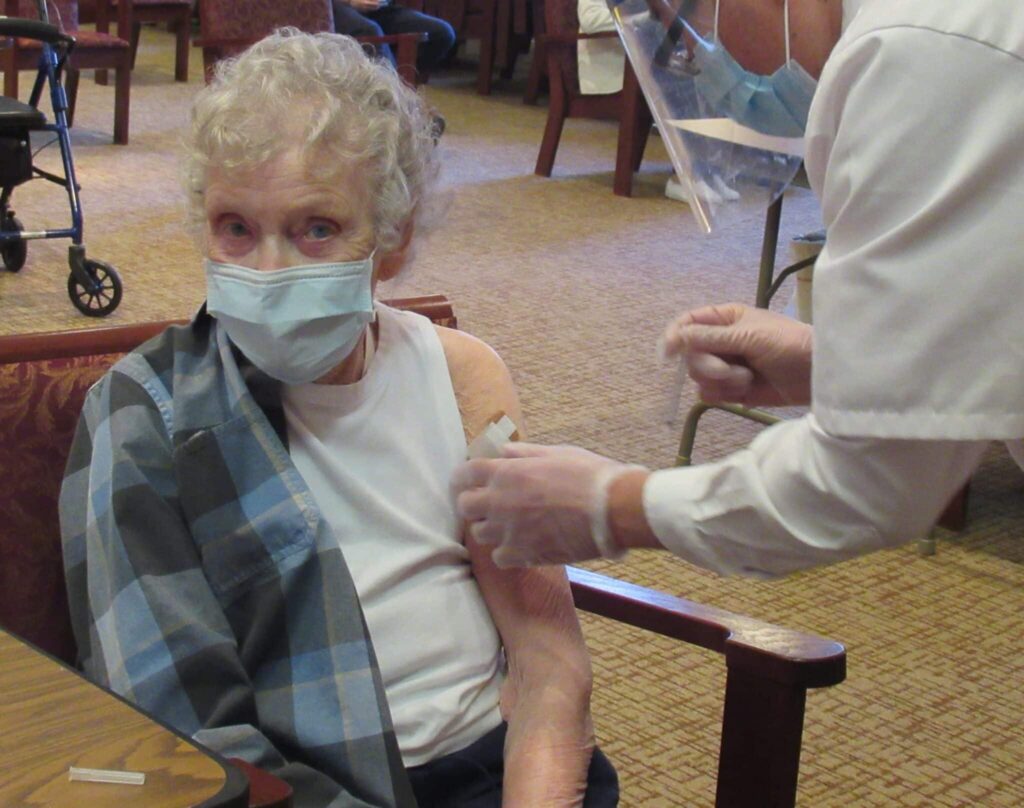 CLV resident, Lois Cook, getting vaccinated from a Walgreens clinical worker.