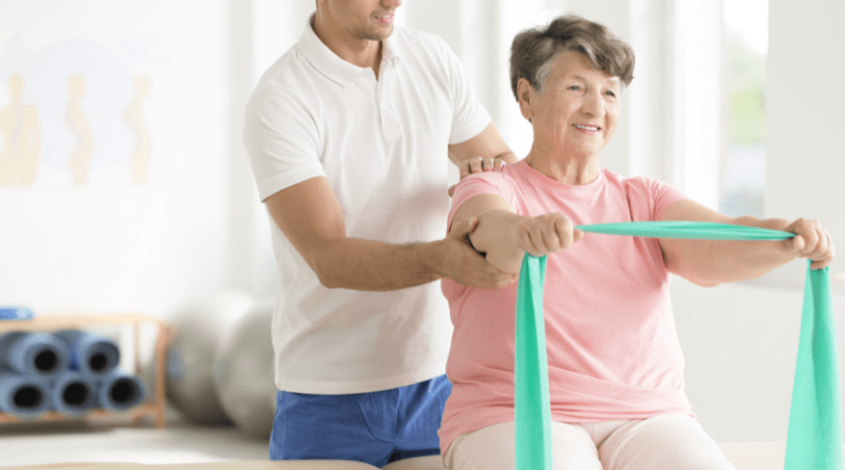 An occupational therapist assisting a female older adult with using a resistance band to improve arm strength.