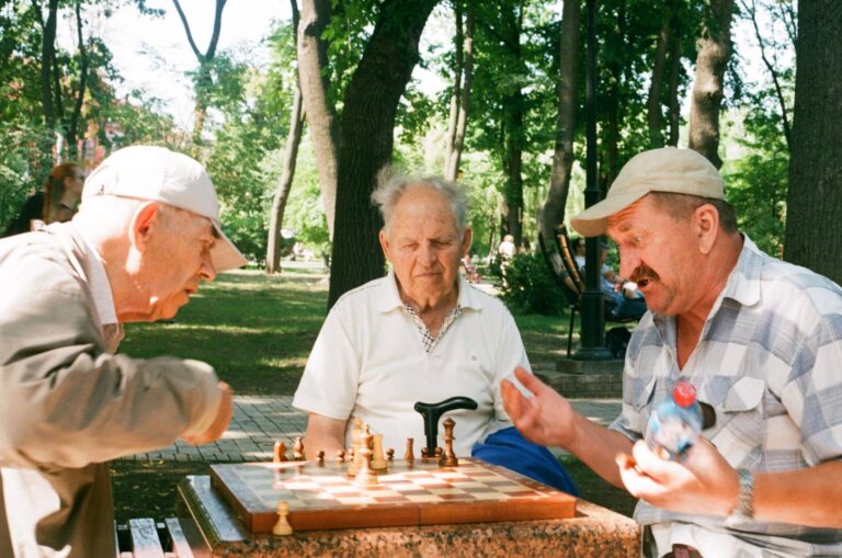 Three men participating in playing a game of chess.