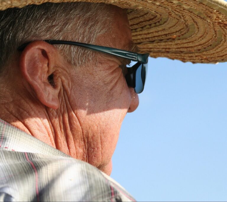 An older man wearing sunglasses and a sun hat
