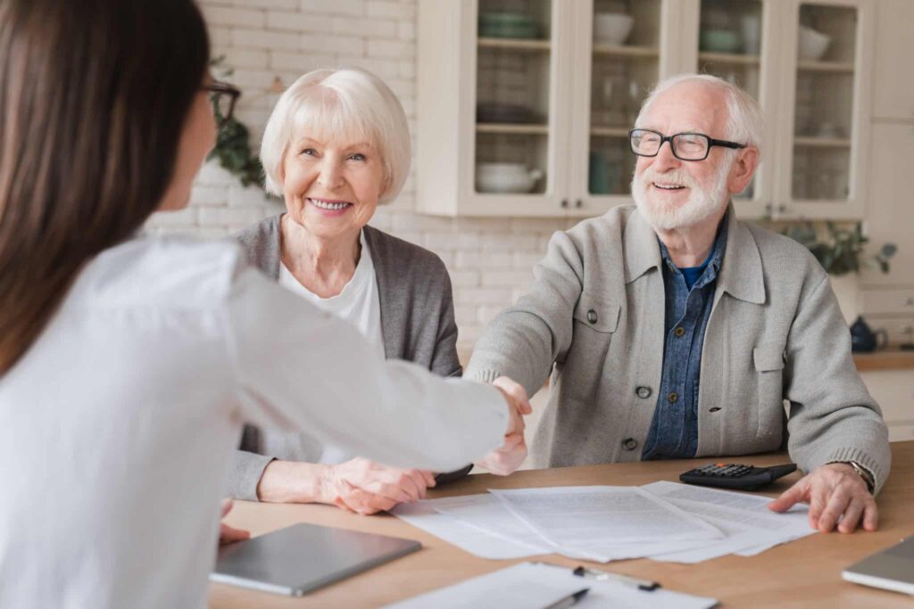 A sales counselor shaking hands with potential residents after comparing the costs of living in a CCRC versus at home.