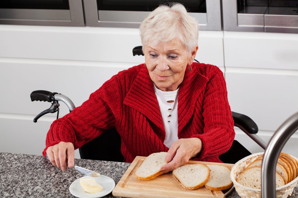 Elderly lady on wheelchair making sandwiches for breakfast