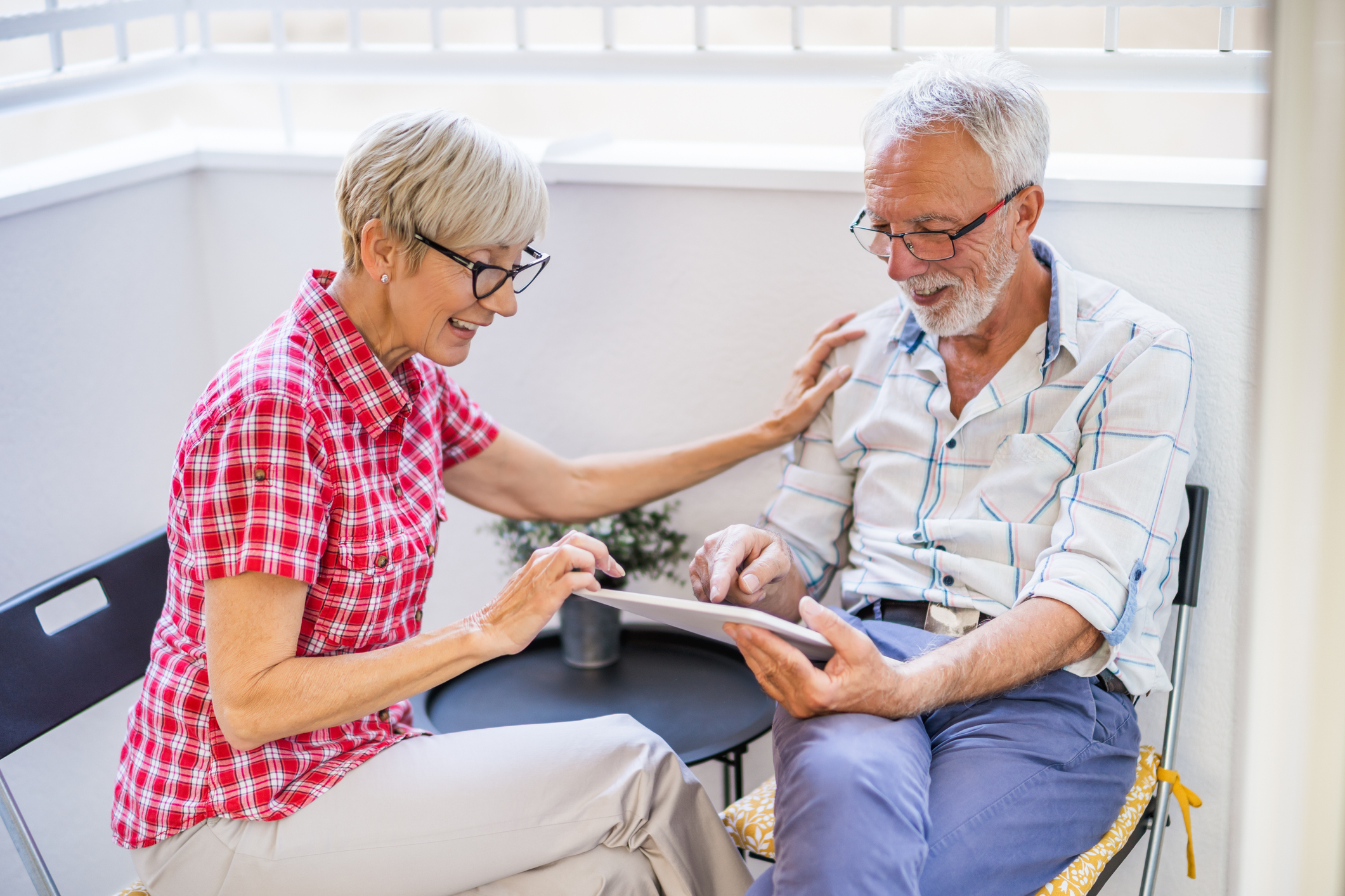 A seated senior woman and man looking at a document, weighing their senior living care options.