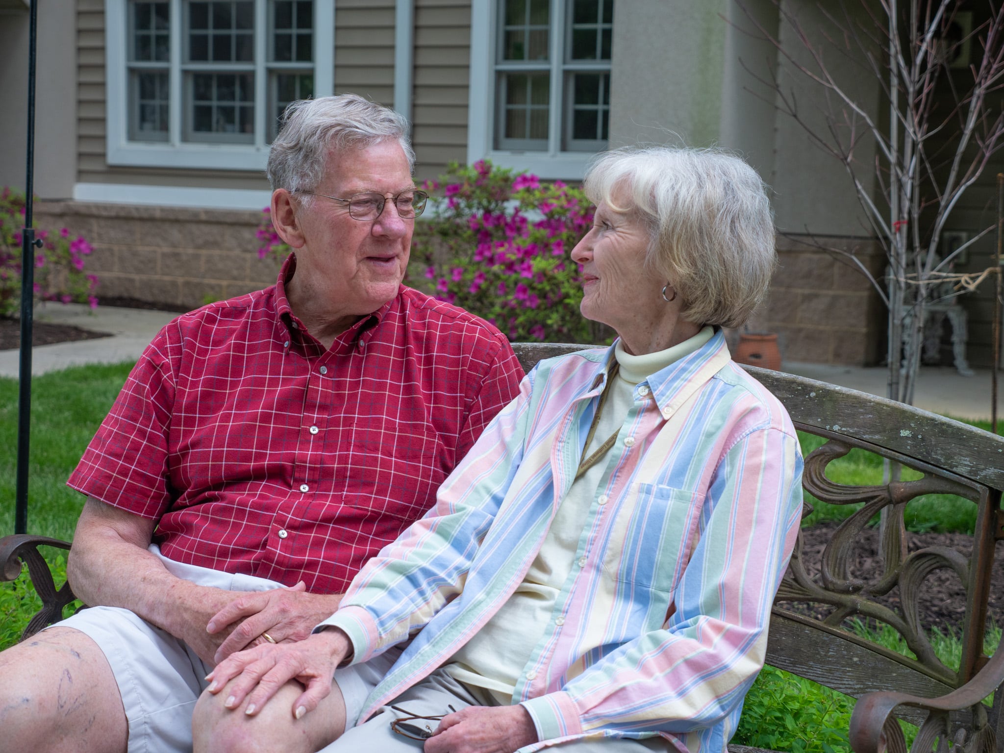 Older couple sitting on bench lovingly looking at one another