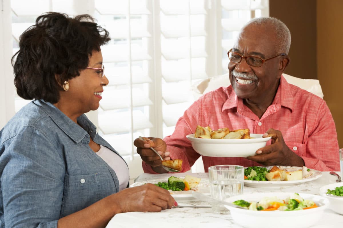 A happy senior couple experiencing how senior living communities have evolved by eating a chef-prepared meal in their community's restaurant.