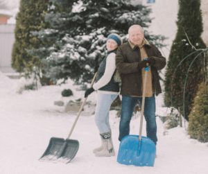 Older adult couple holding shovels in cold weather. 