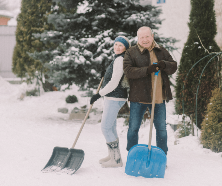 Older adult couple holding shovels in cold weather.