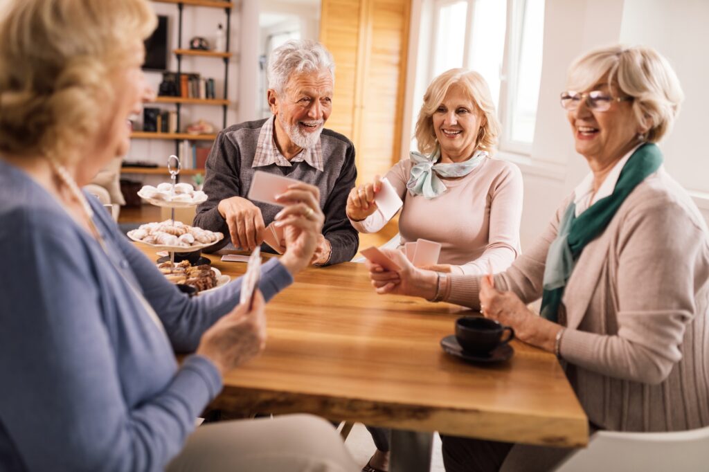 Group of happy seniors playing cards at home.