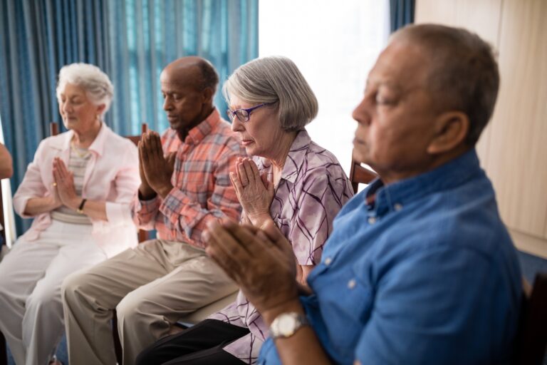 Seniors sitting on chairs while praying