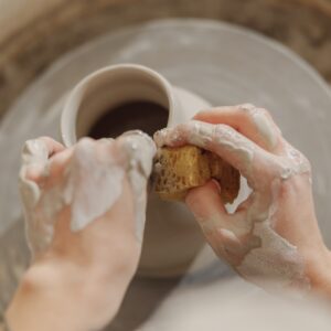 Close up of hands of professional potter molding pot shape on pottery wheel. Ceramics art concept