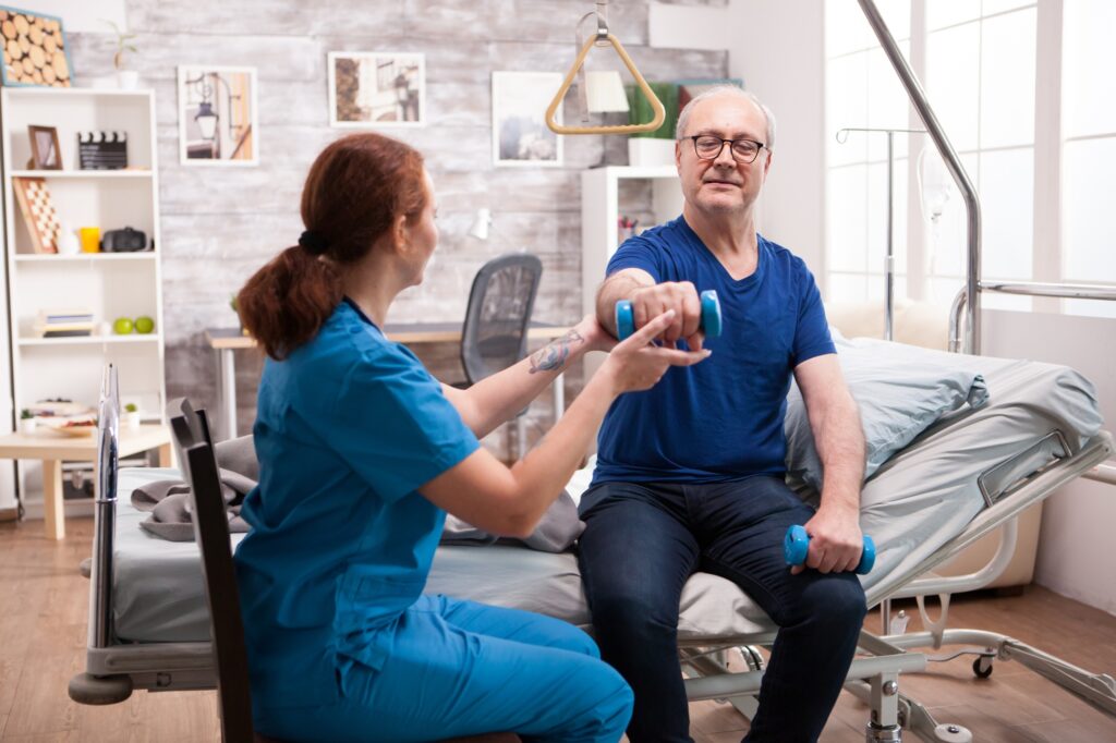 Female nurse helping old in with his rehabilitation