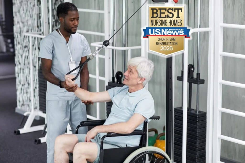 A physical therapist helping an older adult male in a wheel chair improve his upper body strength using a weight-lifting machine as part of his short-term rehabilitation excercises.