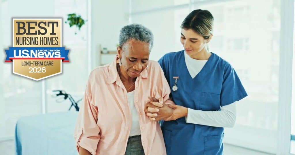 A nurse helping an older adult woman in long-term care walk.