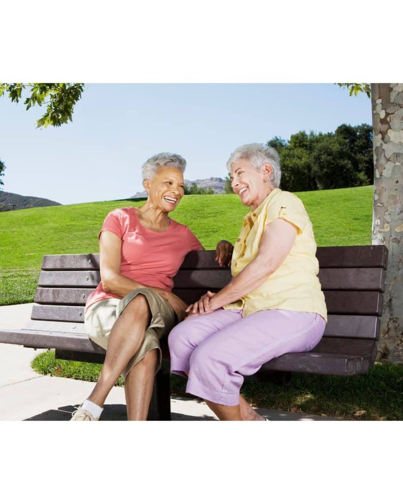 Senior friends sitting on bench making a social connection in the community